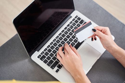 Fille tapant sur le clavier de son ordinateur portable avec une carte bancaire