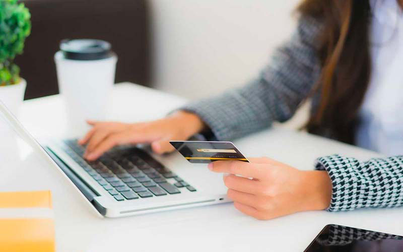 femme sur un ordinateur portable avec sa carte bancaire Prelevement Sogecap