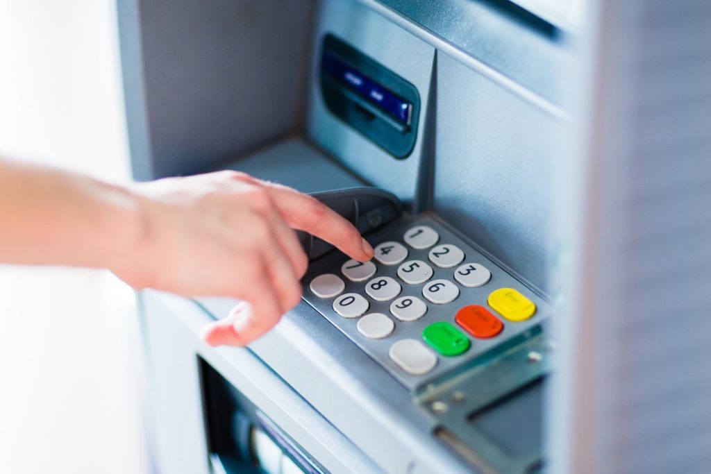Gros plan de la main entrant le code PIN dans un guichet automatique bancair