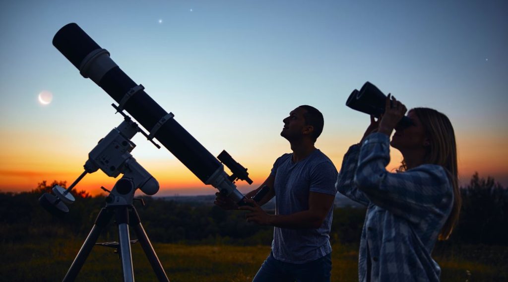 à L'extérieur, Un Homme Avec Un Téléscope Et Une Femme Avec Des Jumelles