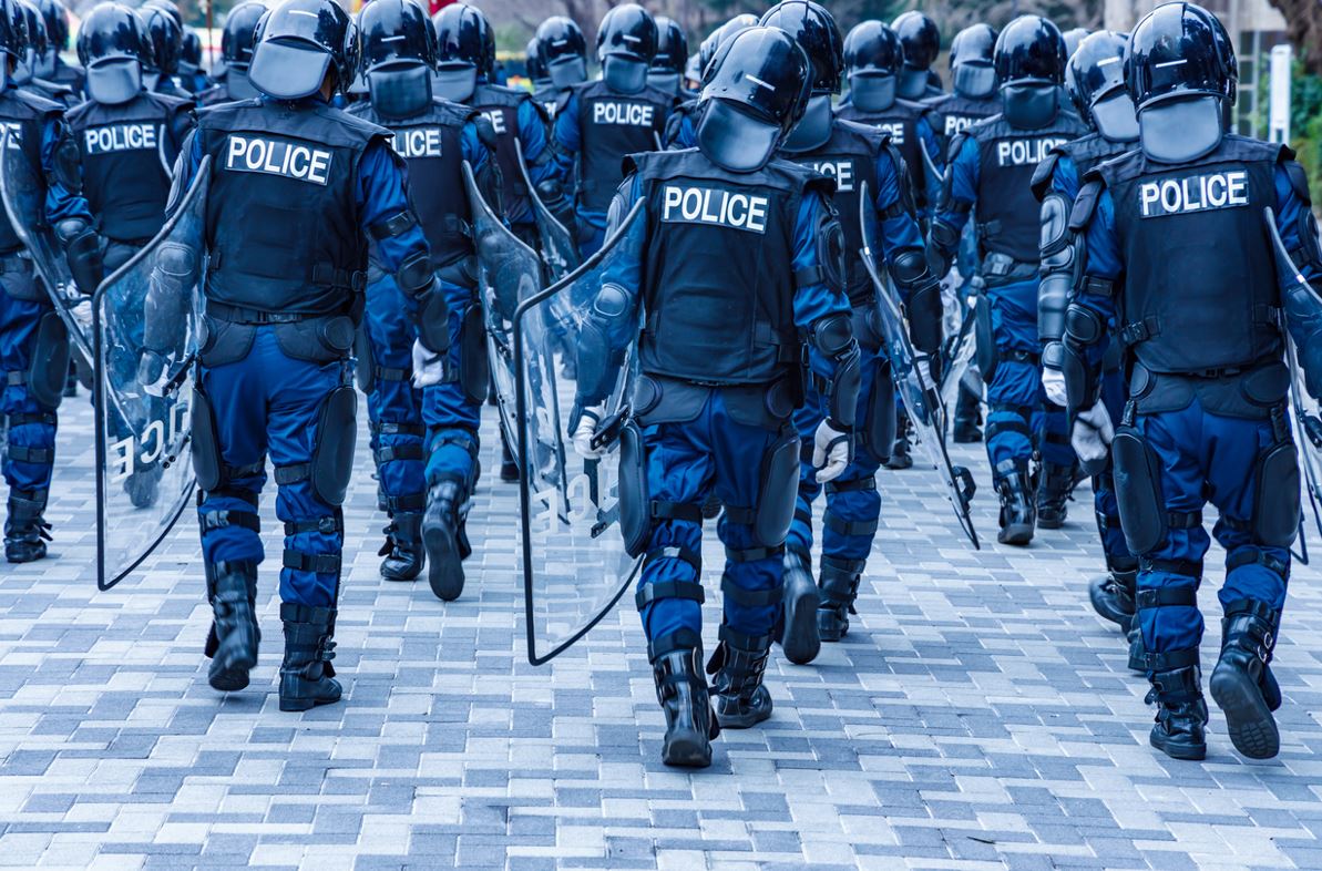 Groupe De Crs Qui Marche De Dos En Tenue, Casque Et Bouclier