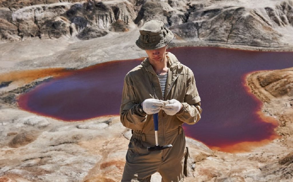 Homme En Haut D'un Volcan Examine Un Rocher