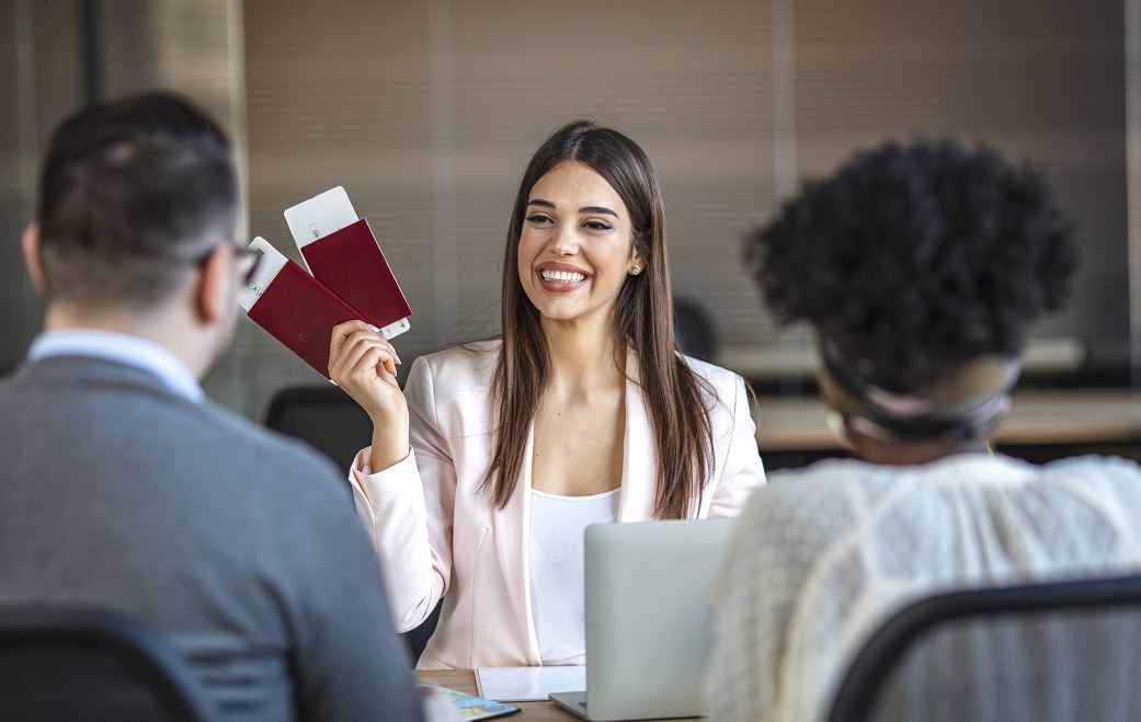 Femme Tenant Des Billets D'avion Devant Un Couple De Clients