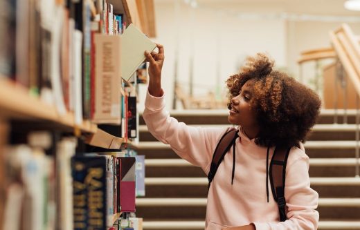 Jeune Fille Qui Choisie Un Livre Dans Une Bibliothèque